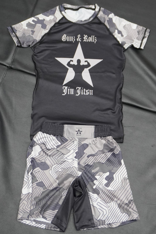 Grey Gunz & Rollz kids' ranked camo rash guard with star logo, black body with grey camo sleeves, flat-lay photo with matching shorts